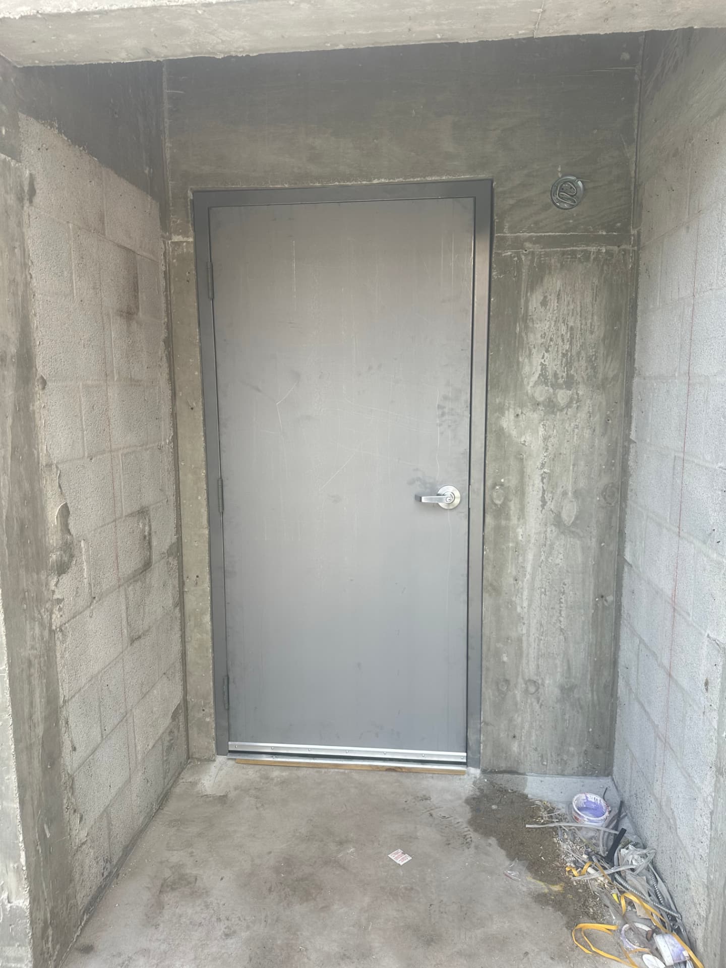 Gray hollow metal door and frame in concrete enclosure